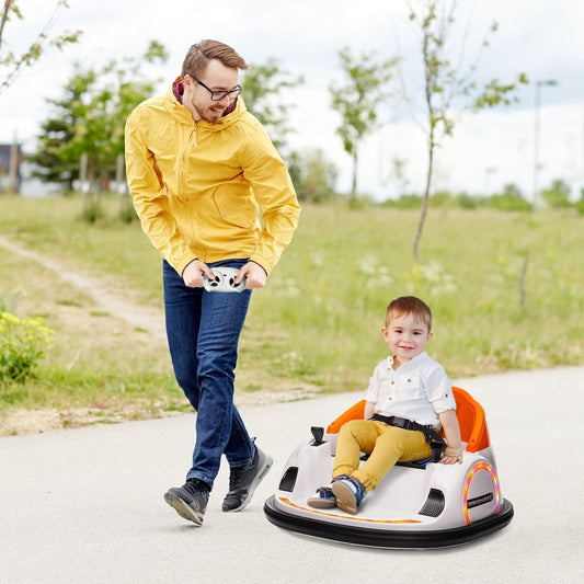 A father watches his son ride the orange kids electric bumper car outdoors