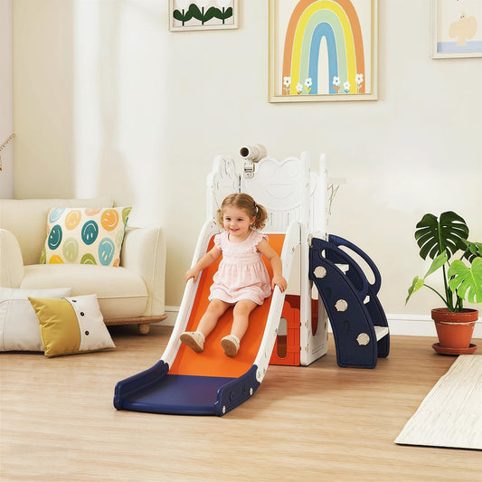 Toddler girl sliding down the orange slide of the kids play set in a living room