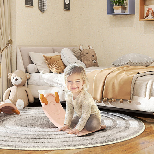 A pink kids balance board in a child's bedroom, with a girl sitting on it