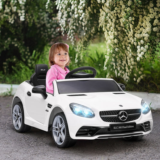 A happy child drives the white kids electric car in a garden setting