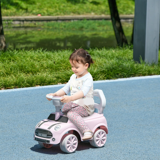 A young child sitting on the pink ride-on car outdoors on a blue path
