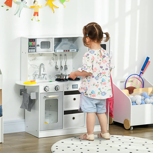 A young child playing with the white and grey role play toy kitchen in a bright room