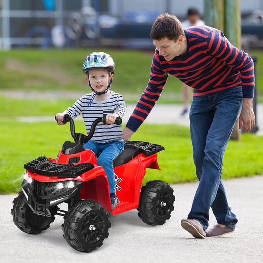 The kids electric car being pushed by a man along a paved path in a park with a child riding