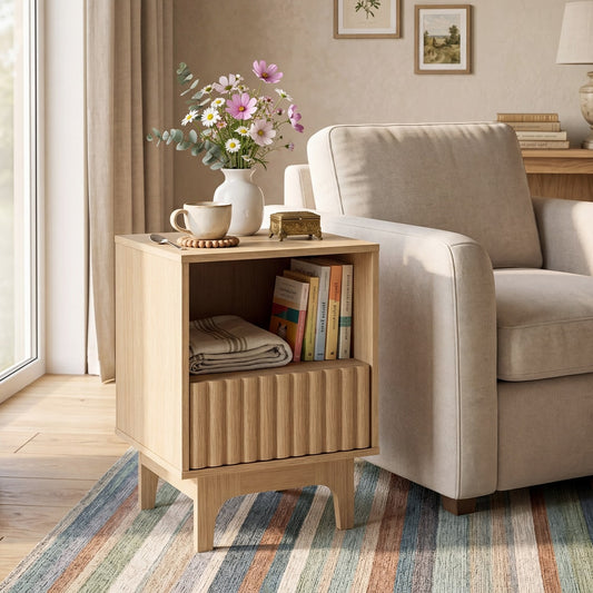 The nightstand styled with a vase of flowers and books next to an armchair