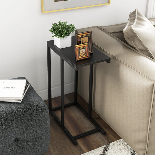 The end table placed beside a sofa holding a small plant and two framed pictures