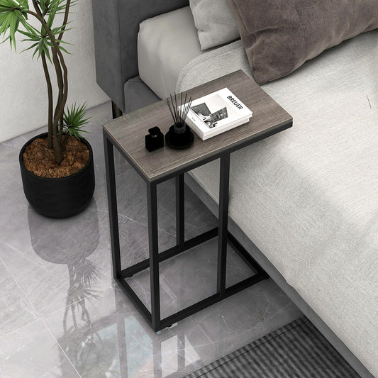 The end table tucked under a bed with a book and plant on top