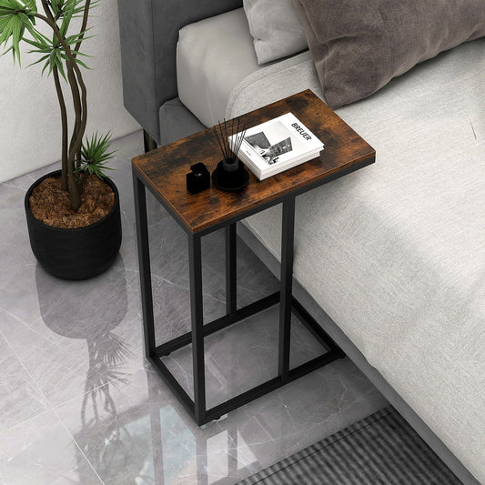 The end table placed beside a bed with books and a small decorative item on the surface