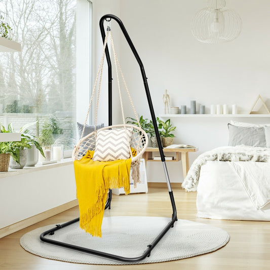 Hammock swing frame with a cream woven chair and yellow throw in a bright room