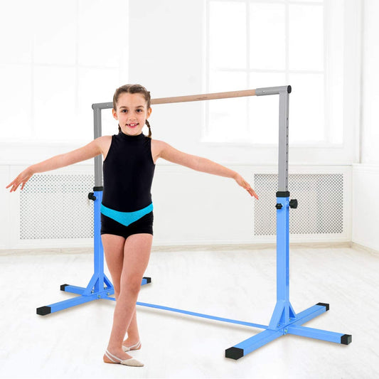 A young girl in gymnastics attire poses next to the kids gymnastics bar in a bright room