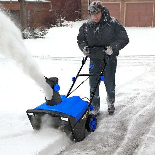 Man using the electric snow blower to clear a snowy driveway