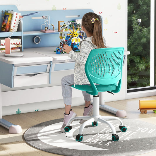 A child sitting at a desk on the green kids study chair, working on a school project