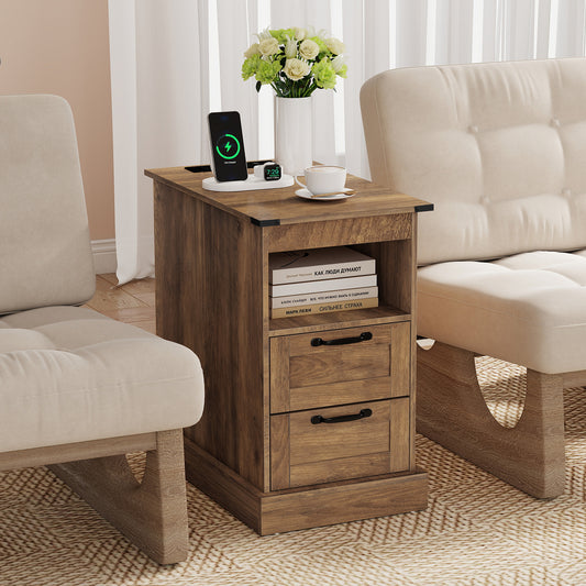 The bedside table positioned between two chairs with a phone charging on top