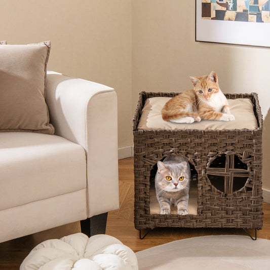 Brown rattan cat house in a living room with a sofa and rug, two cats are visible
