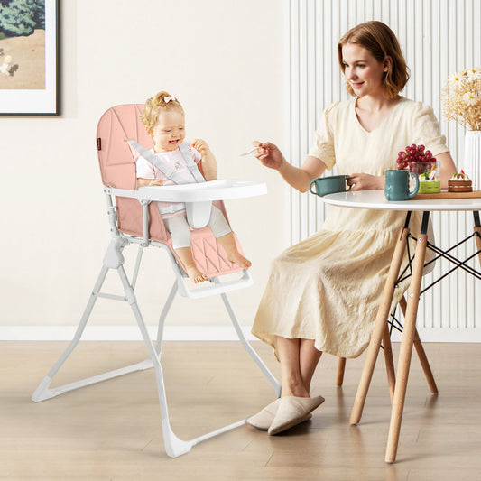 A mother feeding her baby in the pink high chair in a dining room setting
