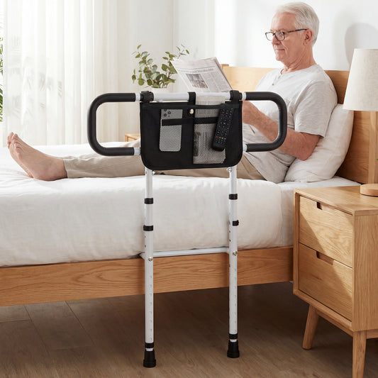 The bed rail is shown in use by an elderly man reading a newspaper in a domestic bedroom