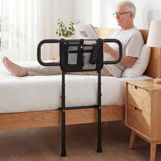 The safety rail installed on a wooden bed frame with an elderly man reading a newspaper in bed