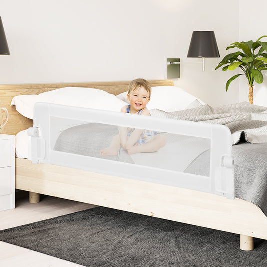 Toddler sitting on a bed with the white bed rail installed