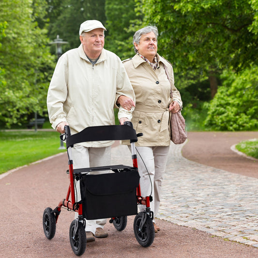 Elderly couple walking in a park with the red rolling walker