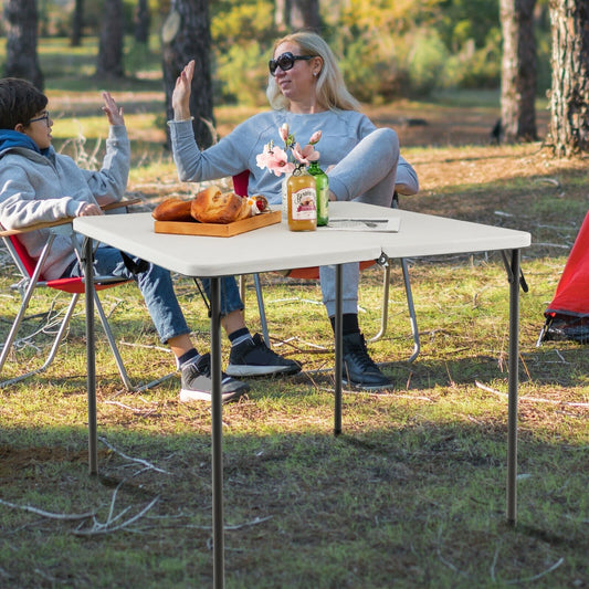 The patio table in use by a family sitting on camping chairs in a sunny woodland area