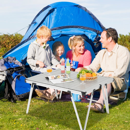 The camping furniture being used by a family for a picnic outside a blue tent