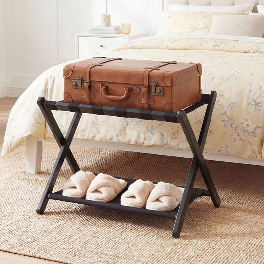 This black luggage rack holds a suitcase and slippers in a bedroom setting