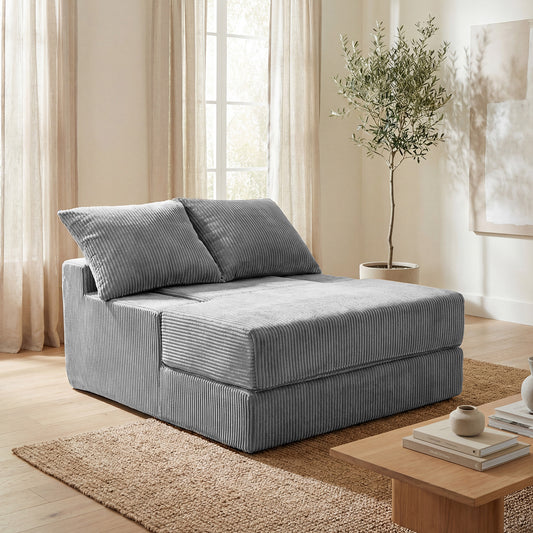 The grey corduroy loveseat in a folded upright position placed on a rug in a bright living room