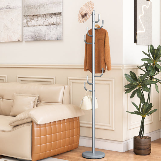 The coat rack standing in a living room next to a sofa with a hat, shirt and bag hanging on it