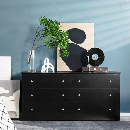 The black chest of drawers placed against a blue wall with decorative items on top