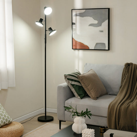 The floor lamp standing in a cosy living room next to a grey sofa and abstract wall art