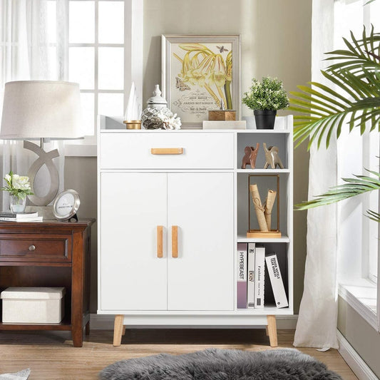 A white wooden bookcase with a drawer and adjustable shelves, shown in a bright room setting with a lamp and plants