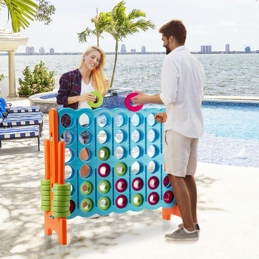 A couple playing the giant four in a row lawn game by a swimming pool