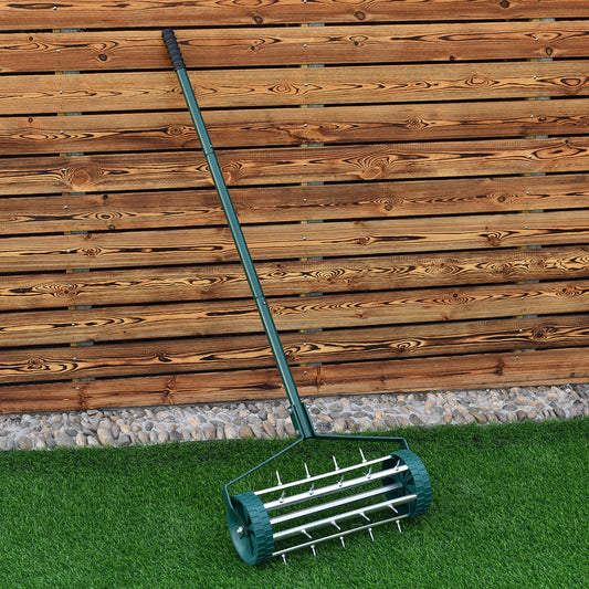 The lawn aerator leaning against a wooden fence on a patch of green grass