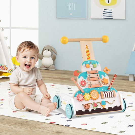 baby sitting next to the colourful cake push walker on a play mat