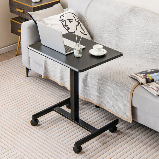 The black rolling standing desk is next to a sofa with a laptop and coffee cup
