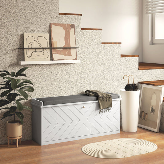 The shoe storage placed in a hallway next to a plant and stairs with a throw blanket on top