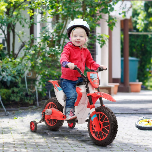 A young child wearing a helmet rides the red and white kids electric motorbike in a garden setting
