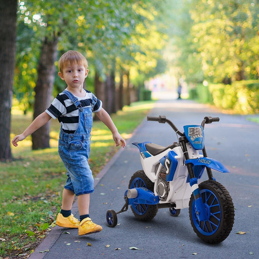 Young boy standing next to the blue kids electric motorbike on a paved path in a park