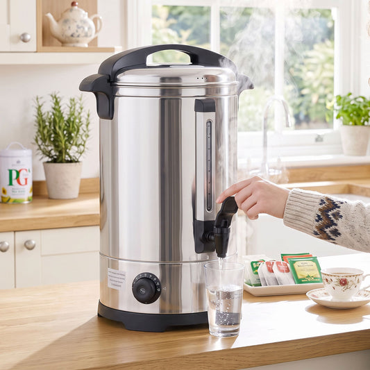 The catering urn dispensing hot water into a glass, with tea bags and a mug nearby
