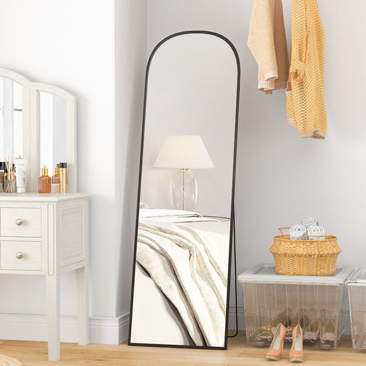 Full length mirror in a bedroom next to a dressing table and basket of towels