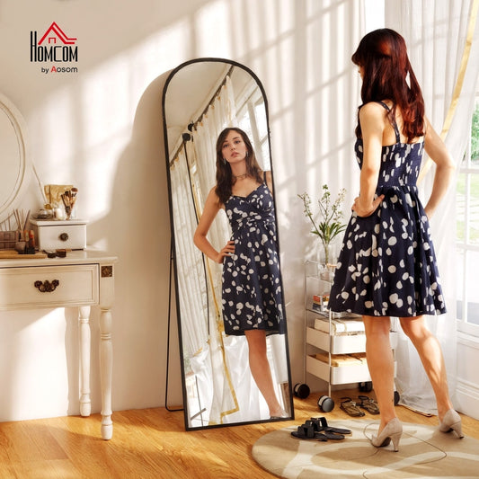 Woman in a polka dot dress trying on the full length mirror in a bedroom setting
