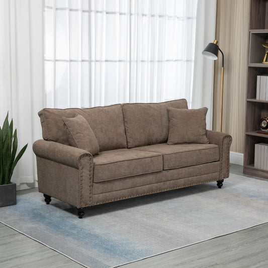 Brown fabric three seater sofa in a living room setting with a bookcase and lamp