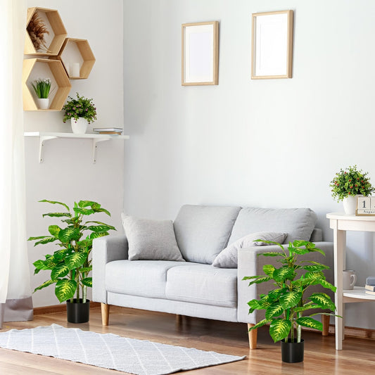 The artificial evergreen tree placed in a living room next to a sofa and a side table