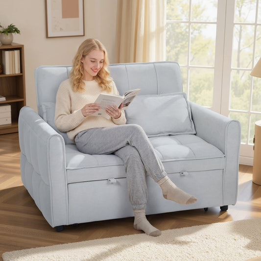 A woman reading a book on the light grey sofa bed in a living room setting