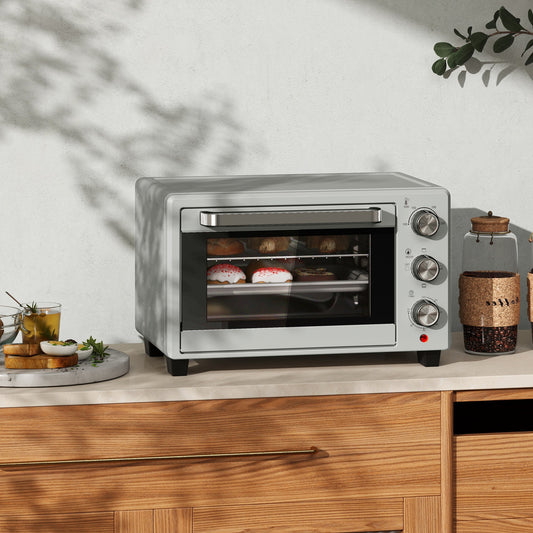 The silver countertop oven placed on a wooden kitchen worktop with food items nearby
