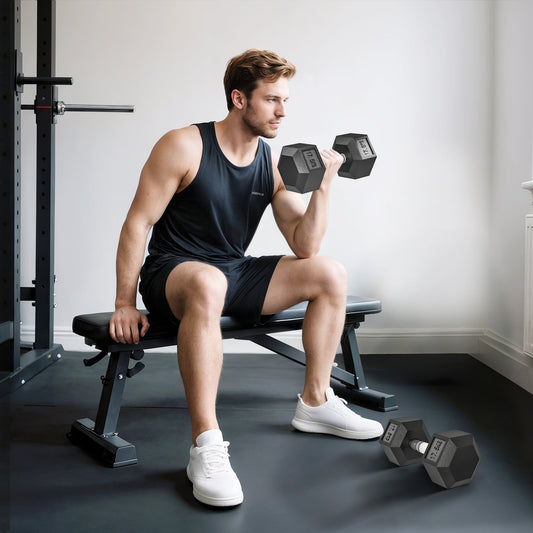 A man sitting on a gym bench lifting one of the rubber hex dumbbells in a home gym setting