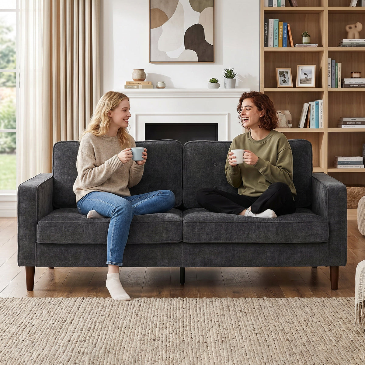 Two women sitting and chatting on the dark grey upholstered sofa