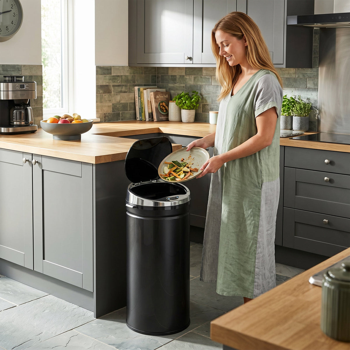 A woman places a plate into the automatic rubbish bin in a modern kitchen