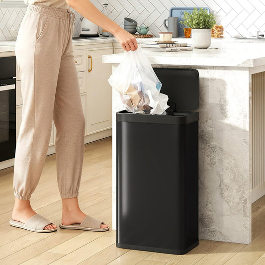 The black kitchen bin in use with a person adding rubbish to the open lid