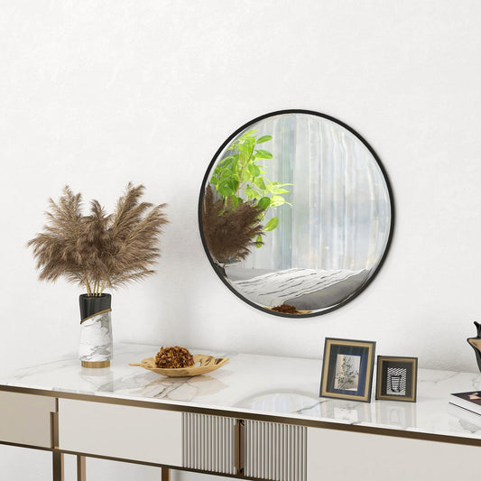A round wall mirror with a black frame placed on a console table with decorative items