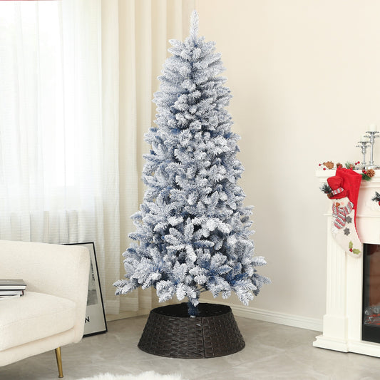 The snowy Christmas tree is set up in a living room next to a fireplace and armchair